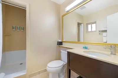 a bathroom with a toilet and a sink and a mirror at Best Western Royal Palace Inn & Suites in Los Angeles
