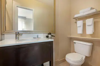 a bathroom with a sink and a toilet and a mirror at Best Western Royal Palace Inn & Suites in Los Angeles