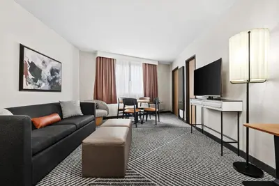 a hotel room with a couch and a tv at Royal Palace Westwood Hotel in Los Angeles