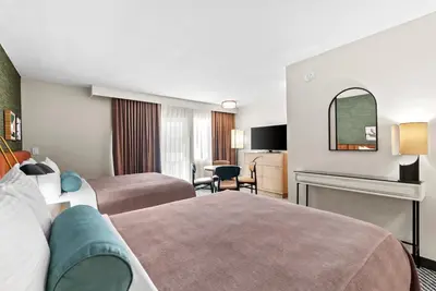 a hotel room with two beds and a chair at Royal Palace Westwood Hotel in Los Angeles