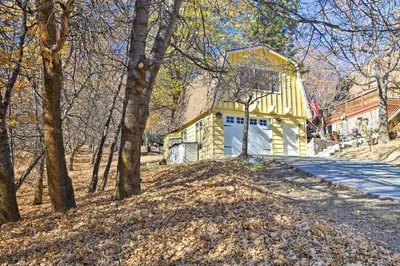 a small yellow and white building in the woods at Lake Arrowhead Studio Near Hiking with Hot Tub in Lake Arrowhead