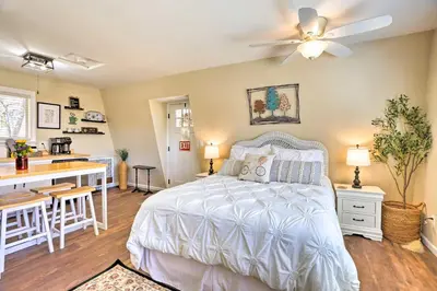 a bedroom with a white bed and a kitchen at Lake Arrowhead Studio Near Hiking with Hot Tub in Lake Arrowhead