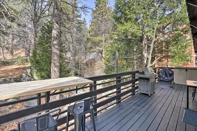 a wooden deck with a grill and a table at Modern Cabin with Game Room and Deck, Near Skiing in Running Springs