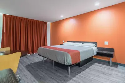 a bedroom with a bed with an orange wall at Motel 6-Barstow, CA - Route 66 in Barstow