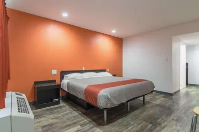 a bedroom with a bed with an orange wall at Motel 6-Barstow, CA - Route 66 in Barstow