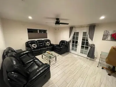 a living room with a black leather couch and a table at Cheerful, Beautifully Remodeled, Modern, Comfortable Home in Los Angeles