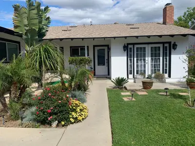 a white house with a yard with flowers at Cheerful, Beautifully Remodeled, Modern, Comfortable Home in Los Angeles