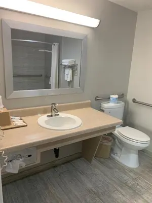 a bathroom with a sink and a toilet and a mirror at Buena Park Inn in Anaheim