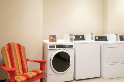 a washing machine and a chair in a room at Home2 Suites By Hilton Woodland Hills Los Angeles in Woodland Hills