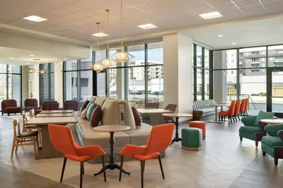 a waiting room with chairs and tables and windows at Home2 Suites By Hilton Woodland Hills Los Angeles in Woodland Hills