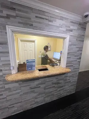 a man standing at a counter in a brick wall at EL PATIO HOTEL in San Bernardino