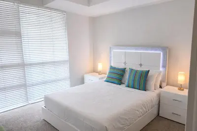 a white bedroom with a large white bed with two lamps at ViewPoint Suites in Los Angeles