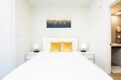 a white bedroom with a large bed with two night stands at ViewPoint Suites in Los Angeles