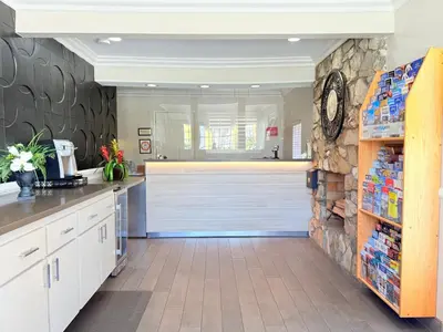 a kitchen with white cabinets and a stone wall at Anaheim Islander Inn and suites near Park and Convention center in Anaheim