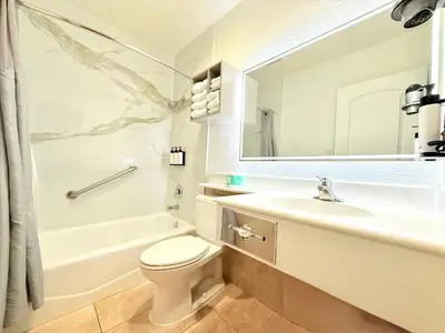 a bathroom with a sink toilet and a mirror at Anaheim Islander Inn and suites near Park and Convention center in Anaheim