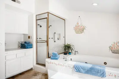 a white bathroom with a tub and a shower at Sandcastle by the Sea in Oxnard
