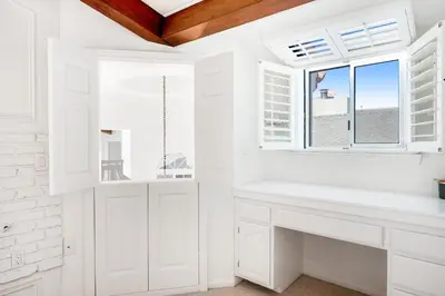 a white kitchen with white cabinets and a window at Sandcastle by the Sea in Oxnard