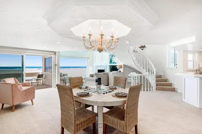a dining room with a table and chairs and the ocean at Sandcastle by the Sea in Oxnard