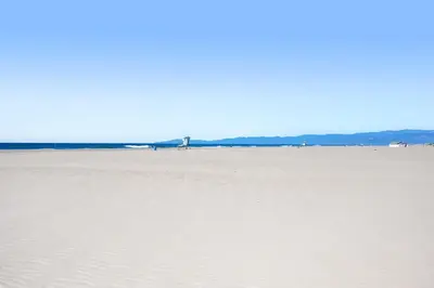 a field of sand with buildings in the distance at Sandcastle by the Sea in Oxnard