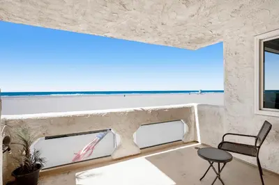 a room with a view of the beach and a chair at Sandcastle by the Sea in Oxnard