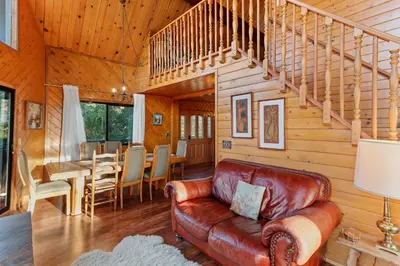 a living room with a leather couch and a staircase at Howard's Cabin in Lake Arrowhead