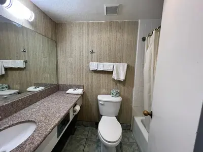 a bathroom with a toilet and a sink and a tub at Casa Playa Inn - Stanton, Anaheim in Stanton