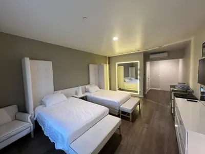 a hotel room with two beds and a couch at ASPIRE INN & SUITES Orange in Orange