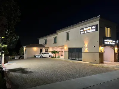 a white car parked in front of a building at night at ASPIRE INN & SUITES Orange in Orange