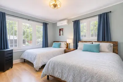 two beds in a bedroom with blue curtains at Modern LA Home Near Museums, Dining & Downtown in Los Angeles