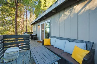 a bench on a porch with yellow and blue pillows at Arrowhead Aerie in Lake Arrowhead
