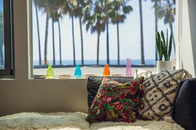 a living room with a couch and a window with palm trees at STAY OPEN Venice Beach in Los Angeles