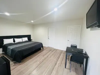 a bedroom with a bed and a desk and a television at Holly Park Motel near LAX in Inglewood