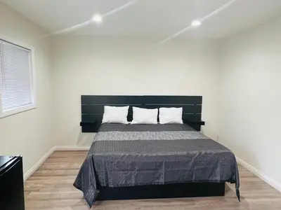 a bedroom with a large bed with a black headboard at Holly Park Motel near LAX in Inglewood