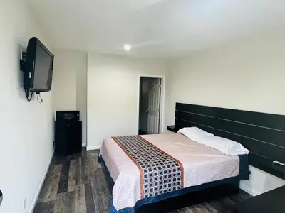 a bedroom with a bed and a flat screen tv at Holly Park Motel near LAX in Inglewood