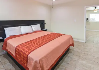 a bedroom with a large bed with a orange blanket at Holly Park Motel near LAX in Inglewood