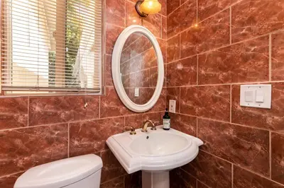 a bathroom with a sink and a mirror and a toilet at Villa Sausalito - Newly Designed 4BR HOUSE & POOL by Topanga in Los Angeles