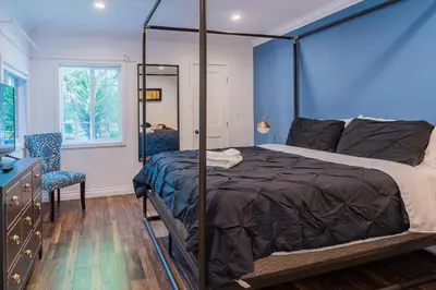 a bedroom with a canopy bed and a chair at Le Bleu House - Newly Designed 3BR HOUSE & POOL by Topanga in Los Angeles