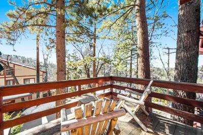a wooden bench sitting on a deck with trees at The Valley's Cabin in Green Valley Lake