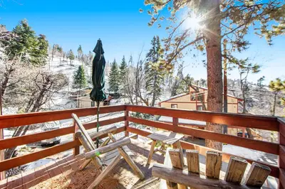 a deck with a bench and an umbrella at The Valley's Cabin in Green Valley Lake
