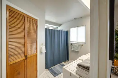 a bathroom with a wooden door and blue curtains at Private Pool and Patio Pet-Friendly Bakersfield Gem in Bakersfield