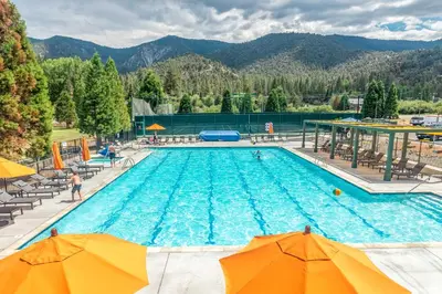 a large swimming pool with chairs and umbrellas at Luxe Escape with Decks, Mtn Views, Game Room! in Frazier Park