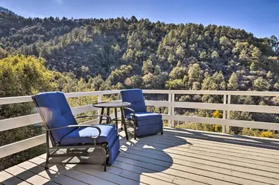 two chairs and a table on a deck with a mountain at Luxe Escape with Decks, Mtn Views, Game Room! in Frazier Park
