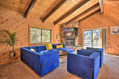 a living room with blue couches and a fireplace at Luxe Escape with Decks, Mtn Views, Game Room! in Frazier Park