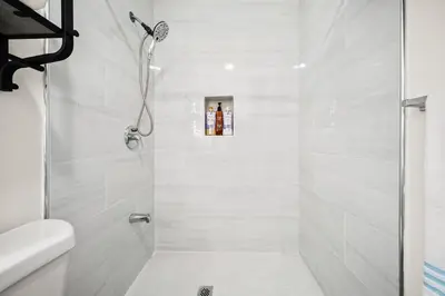 a white bathroom with a shower with a glass door at Dreamy & Relaxing Gem With Backyard - 12mins to DT LA in Alhambra