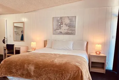 a bedroom with a large bed with two tables and two lamps at Foghorn Harbor Inn in Los Angeles