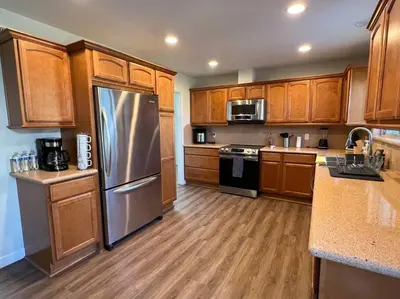 a kitchen with wooden cabinets and a stainless steel refrigerator at Beautiful and Cozy 4-BR residential home!!! in Oxnard