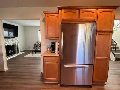 a kitchen with a stainless steel refrigerator and wooden cabinets at Beautiful and Cozy 4-BR residential home!!! in Oxnard