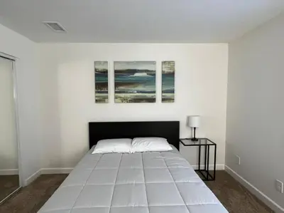 a bedroom with a large white bed with three paintings on the wall at Beautiful and Cozy 4-BR residential home!!! in Oxnard
