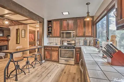 a kitchen with wooden cabinets and a counter with stools at Woodsy Twin Peaks Getaway with Hot Tub and Views! in Twin Peaks
