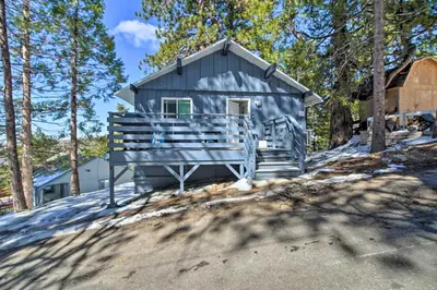 a gray house with a porch in the woods at Chic Running Springs Forest Cabin with Deck! in Running Springs